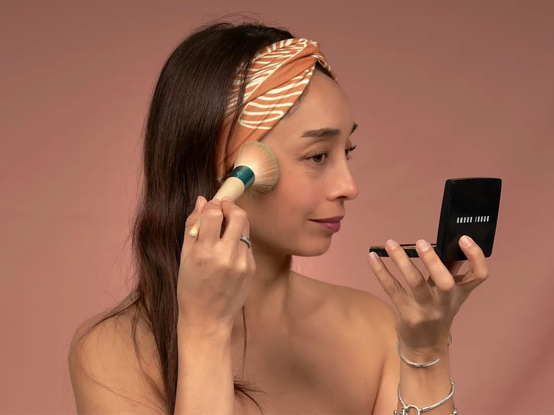 Woman applying blush wearing a printed spa headband